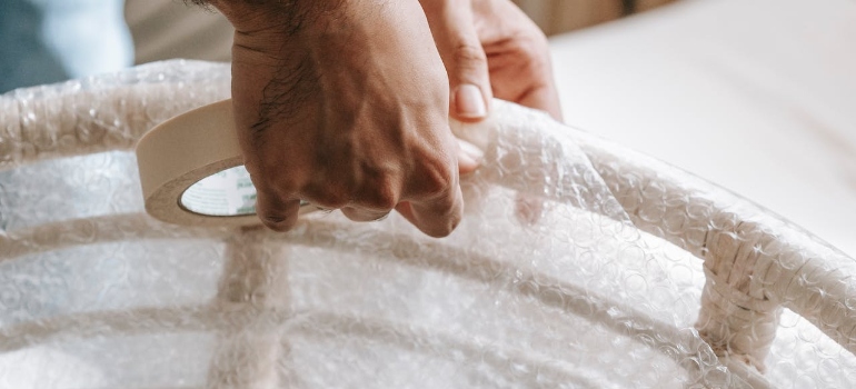 Person wrapping a white wooden chair