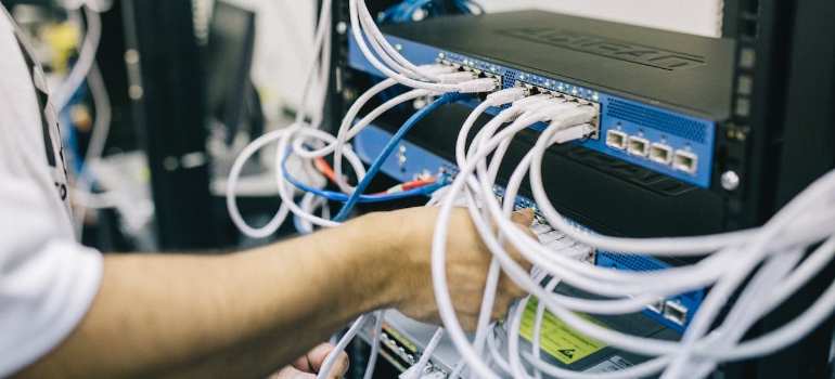 Electronics engineer setting up cables on server as a part of IT Equipment and Electronics Logistics