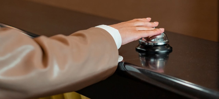 A person in brown leather jacket holding silver reception bell for hospitality and FF&E logistics services